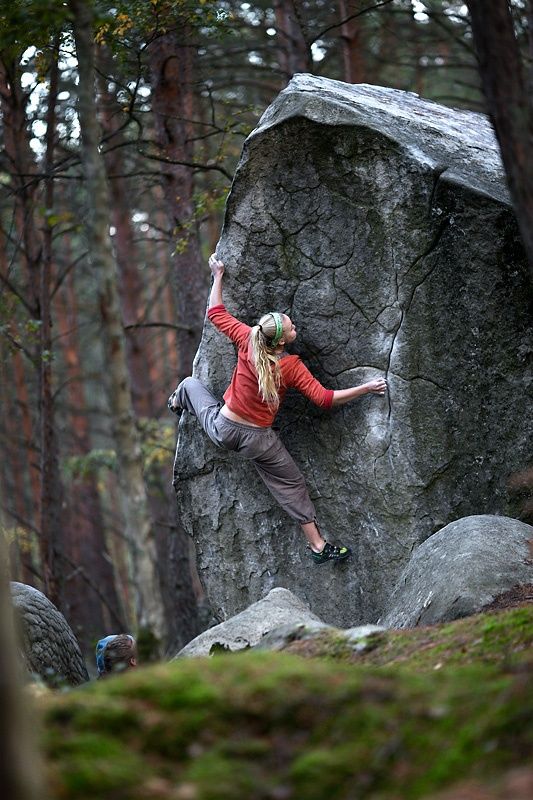 Woman spread out as she is hanging on to a large rock